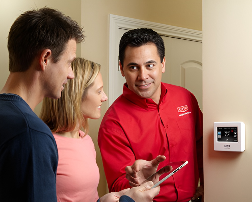 Person showing a thermostat to homeowners